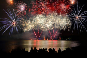 Beautiful large colorful fireworks display with unrecognizable crowd people watching