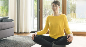 Portrait of woman sitting on the floor of living room floor meditating