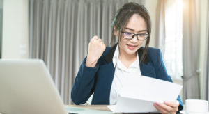 Portrait of an excited woman reading good news in a letter at home