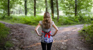 Young woman considering which path to take, right or left.