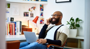 Cheerful businessman working from home on phone