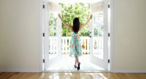 Woman standing in doorway with arms stretched out, rear view