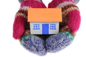 Wool mittens holding a small house